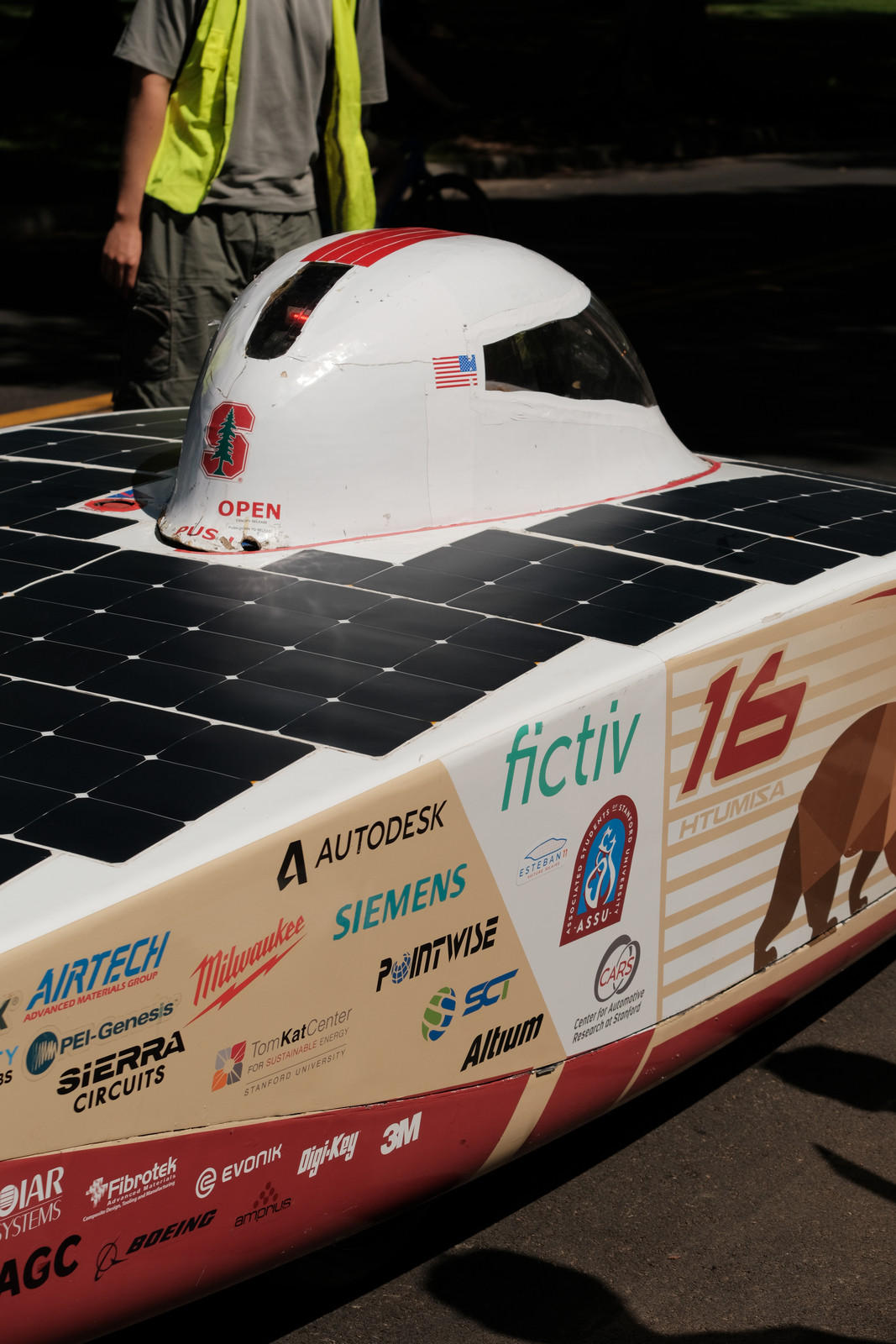 Stanford's solar car, its array and sponsor decals lit by
             low sun